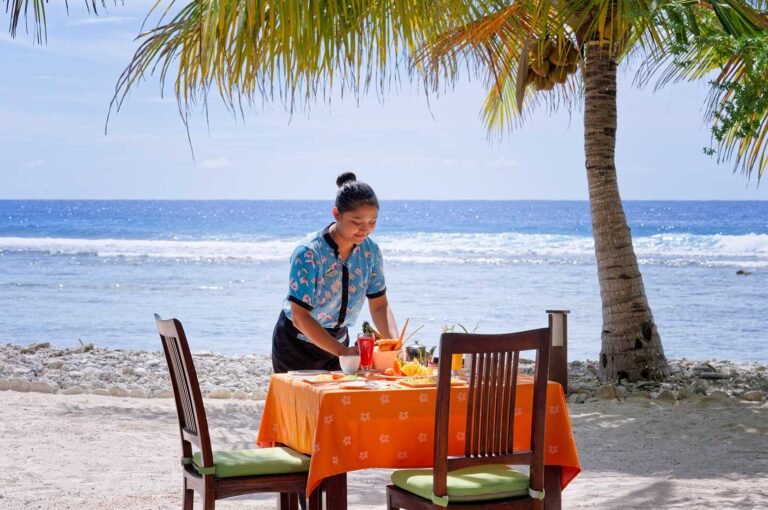 A server arranging a table by the beach at Canareef Resort Maldives